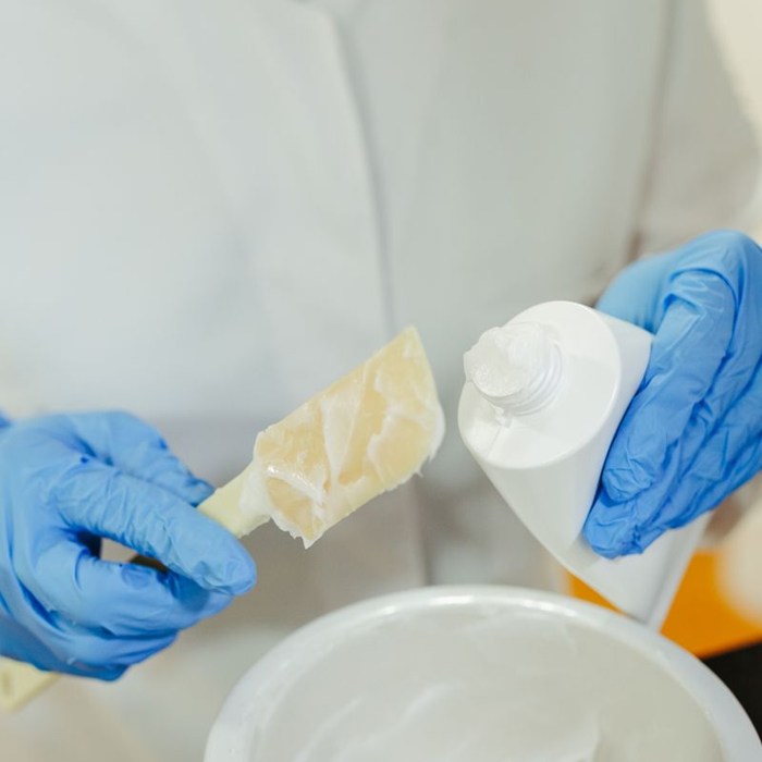 Lab technician mixing a cream sample with a spatula